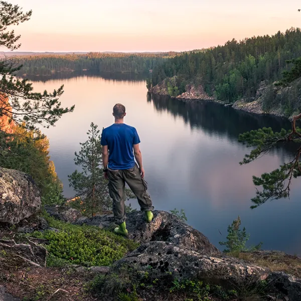 Mies seisoo kalliolla ja katsoo järvelle.